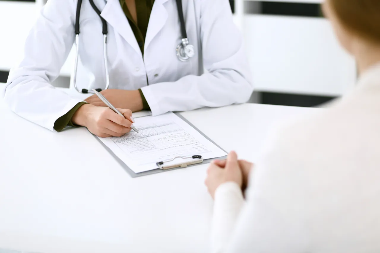 Doctor taking notes on a clipboard while speaking with a patient 